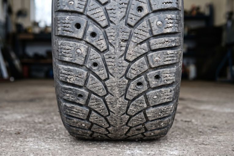 A worn studded tyre with empty stud holes in the tread